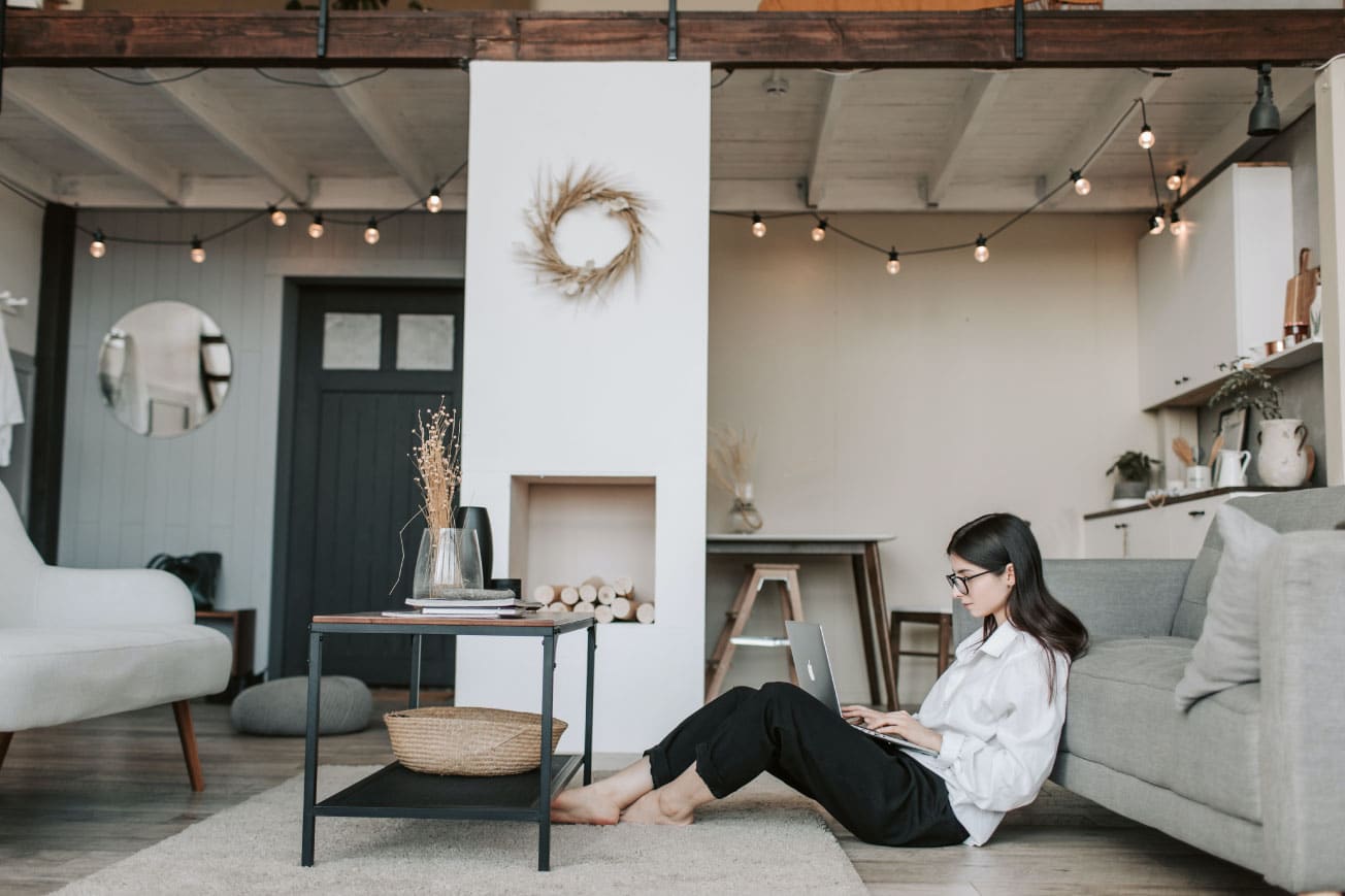Woman working on a laptop in a modern living room, emphasizing home office setup and comfortable environment for potential homebuyers exploring down payment assistance options.