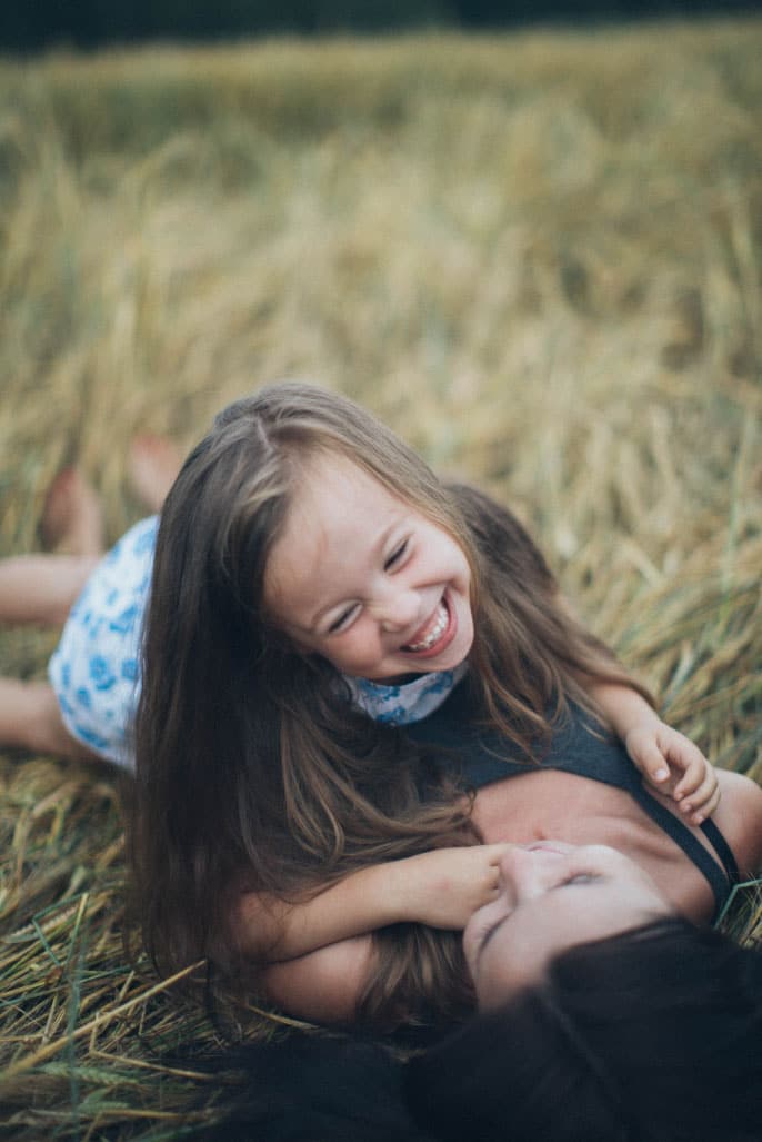 Mother and daughter playing joyfully in a field, highlighting family bonding and happiness.