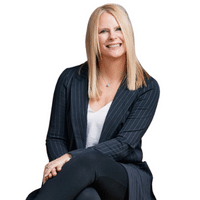 Professional woman smiling, dressed in a dark blazer and white top, representing the Arvold Mortgage Team.