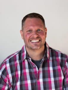Smiling man in a plaid shirt, representing Refined Lending's approachable banking services.