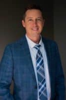 Dave Kelly, Mortgage Loan Originator at Refined Lending, smiling in a professional suit, representing mortgage services for Infinite Campus employees and families.