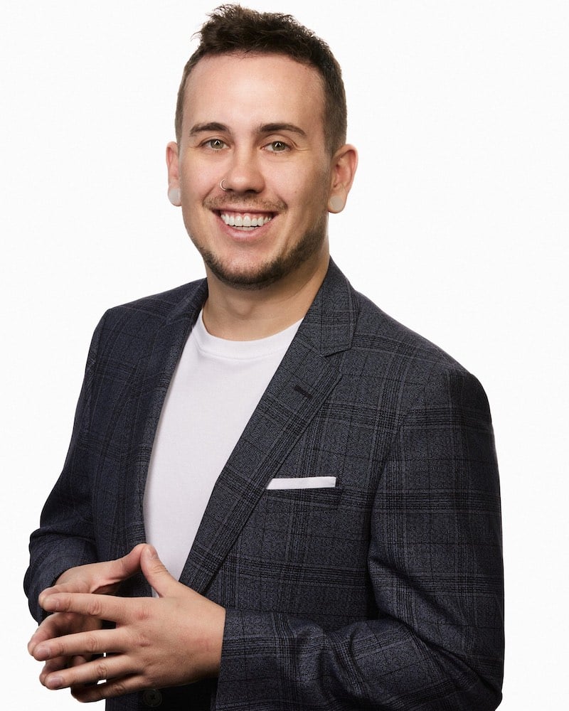 Smiling man in a plaid blazer, hands clasped, representing professional image for Refined Lending.