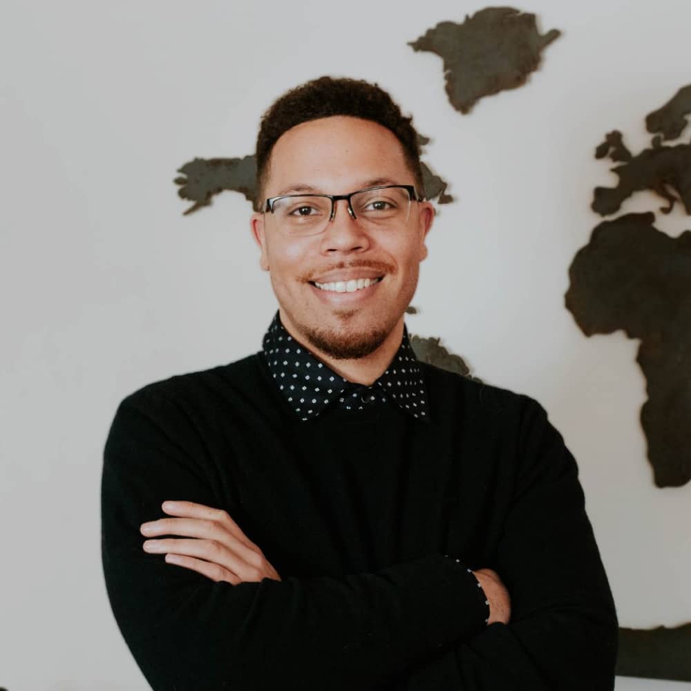 Andrew Mitchell, Mortgage Loan Originator at Refined Lending, smiling with arms crossed in front of a world map backdrop.