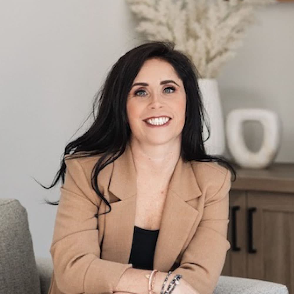 Nikki Syring, Mortgage Loan Originator at Refined Lending, smiling in a professional setting with neutral decor.