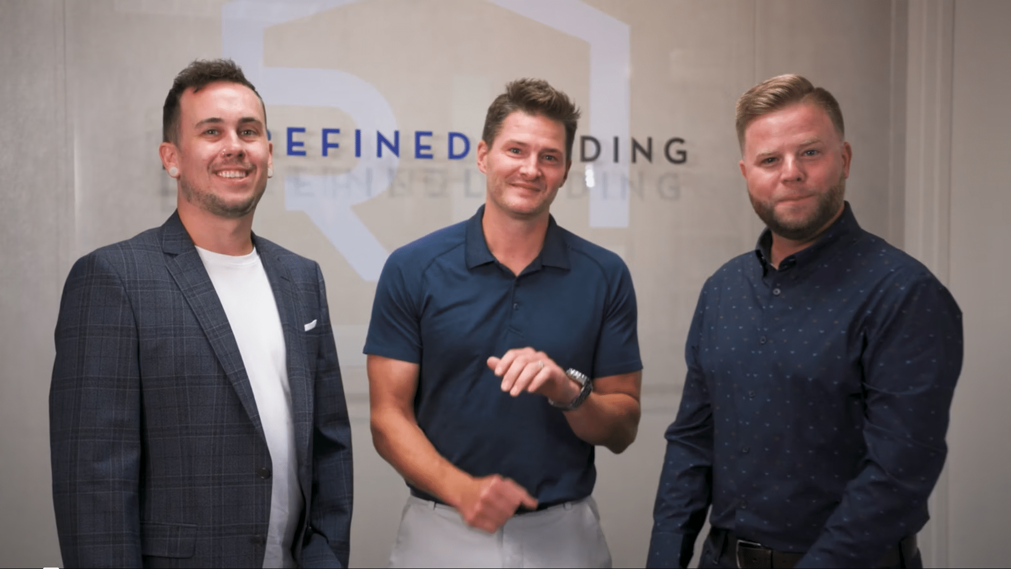 Three loan officers from Refined Lending smiling and interacting in a professional setting, showcasing positive client relationships and customer service.