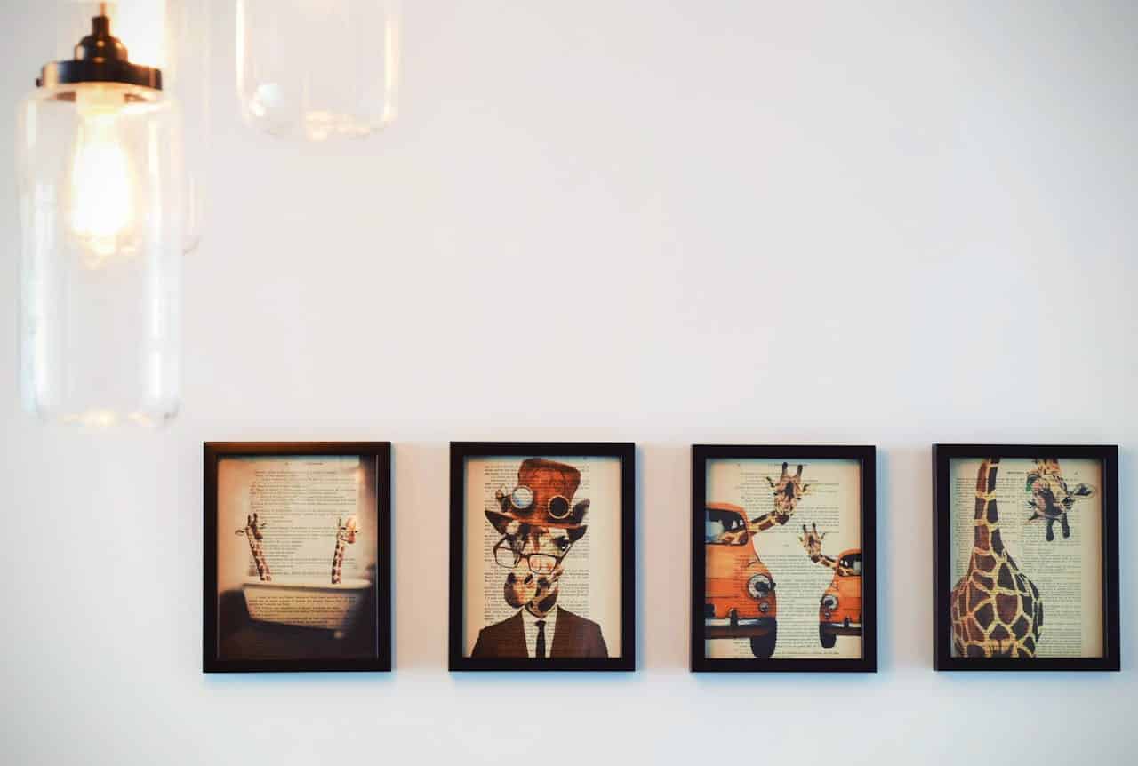 Framed art pieces featuring whimsical giraffe illustrations with vintage elements, displayed on a wall, enhancing the creative ambiance.